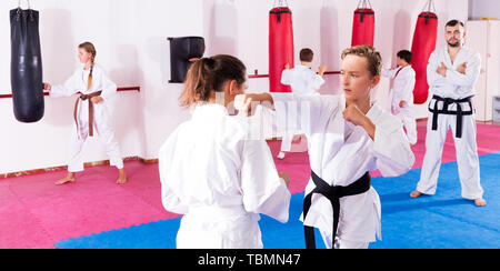 Portrait von Kindern in paar Beherrschung neuer Karate bewegt sich während der Gruppe Klasse mit männlichen Trainer Stockfoto