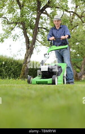 Ein Mann mit einem Rasenmäher in seinem Garten Stockfoto