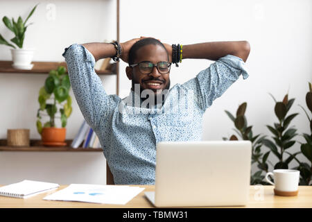 Lächelnd afro-amerikanischen Geschäftsmann, Hände hinter dem Kopf sitzen im Büro Stockfoto