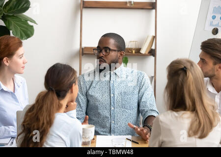 Tausendjährige männlichen Geschäftsmann in Gläsern im Gespräch mit Kollege im Büro Stockfoto