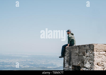Mann mit Kappe sitzt Rückseite Blick von oben von Gebäude Stockfoto