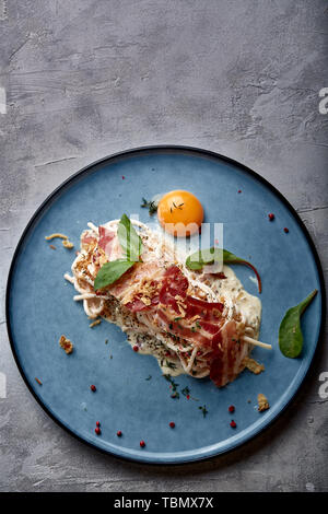 Classic Pasta Carbonara mit Eigelb auf einem Teller. Nudeln auf einem blauen Platte auf einem dunklen Hintergrund. Konzept der Italienischen Küche, schöne dienen Stockfoto