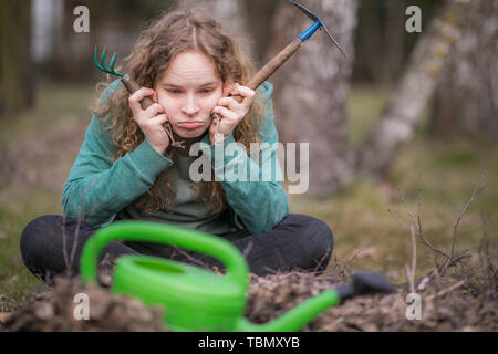 Junge Langeweile Frau beim Frühjahrsputz im Garten Stockfoto