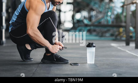 Sportler Schnürsenkel binden, bereit für Workout im Fitnessraum Stockfoto