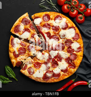 Heiß in Scheiben geschnittene Pepperoni Pizza auf Schwarz Tabelle Stockfoto