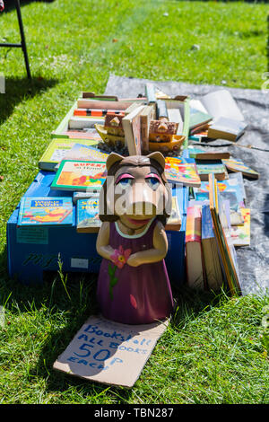 Eine keramische Miss Piggy Figur vor einer Auswahl von Second Hand Bücher der Kinder auf ein Stück Plastik zu einem carboot Verkauf Stockfoto