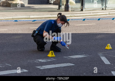 Ein CSI für die Wiltshire Polizei mit footcovers Handschuhe und Gesichtsmaske mit Putzlappen Blut Beweise nach einem Zwischenfall mit einem Messer zu sammeln Stockfoto