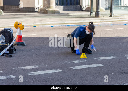 Ein CSI für die Wiltshire Polizei mit footcovers Handschuhe und Gesichtsmaske mit Putzlappen Blut Beweise nach einem Zwischenfall mit einem Messer zu sammeln Stockfoto