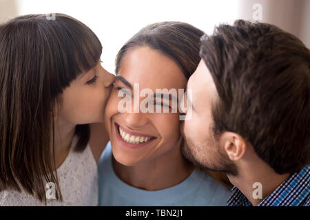 Liebevoller Vater und Tochter küssen Lächeln Mama auf Wangen Stockfoto