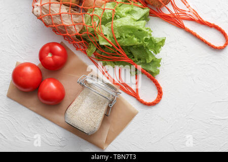 Glas Glas mit Getreide, frisches Gemüse in der Mesh-Shopping Bag auf weißem Hintergrund. Null Abfall Konzept Stockfoto