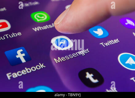 Finger, mit dem ein Symbol auf einem Smartphone oder Tablet-PC Touchscreen die Facebook Messenger social media Messaging App zu laden. Stockfoto