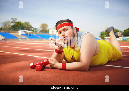 Funny Fat Man macht einen Kuss auf die Spur im Stadion. Stockfoto