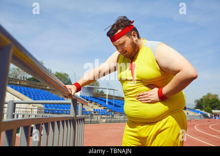 Bauchschmerzen in ein fetter Mann in Sportkleidung in der Ausbildung im Stadion. Stockfoto