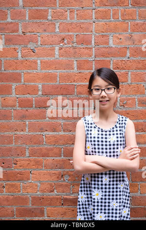 Portrait von jungen asiatischen Mädchen gegen Red brick wall Stockfoto