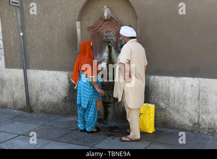 Asiatische paar Füllung Kunststoff Flasche Wasser aus einem öffentlichen Brunnen in Brescia, Italien Stockfoto
