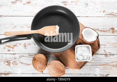 Komposition mit Pfanne und Kokos Öl auf Holz- Hintergrund Stockfoto
