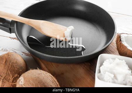 Holzspachtel mit Kokos Öl in der Pfanne auf dem Tisch Stockfoto