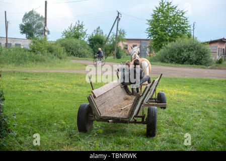 Litynia Dorf, Ukraine - Juni 02, 2018: Zwei junge Jungen reiten auf einem alten hölzernen Wagen. Das Leben in einem Dorf. Stockfoto