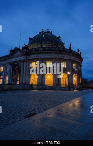 Wunderschöne Aussicht auf eine leere und nassen Brücke vor beleuchtete Bode-Museum auf der Museumsinsel in Berlin, Deutschland, in der Dämmerung. Stockfoto