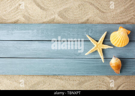 Summer time concept with sea shells and starfish on a blue wood on sand background, Stockfoto