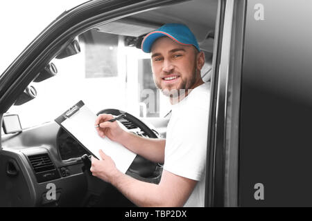 Stattliche delivery man im Auto sitzen Stockfoto