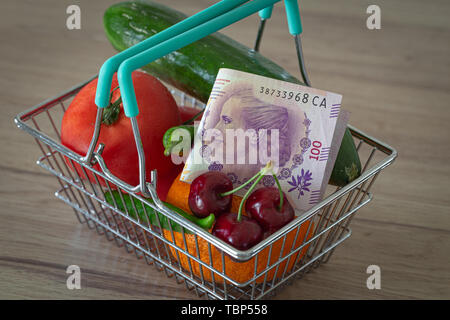 Gemüse und Früchte in den Warenkorb zusammen mit argentinischen Geld / das Konzept der Nahrungsmittelpreise erhöhen Stockfoto