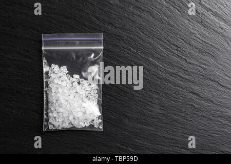 Weiße Kristalle Drogen methamphetamine in einem Plastikbeutel auf schwarzem Hintergrund Stockfoto