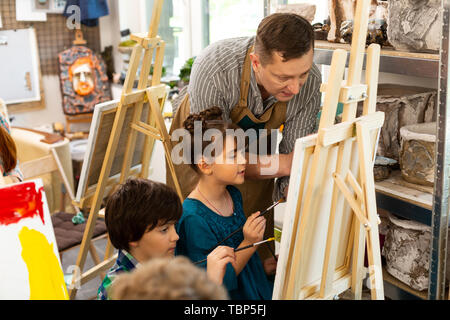 Färbung Bilder. Kunst Lehrer sprechen mit Jungen und Mädchen, während die Färbung Bilder in der Werkstatt Stockfoto