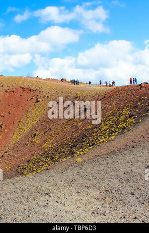 Touristen stehen am Rand von Silvestri Krater auf den Ätna auf der italienischen Insel Sizilien. Die atemberaubende vulkanische Landschaft ist ein beliebtes Touristenziel. Vertikale Fotografie. Stockfoto