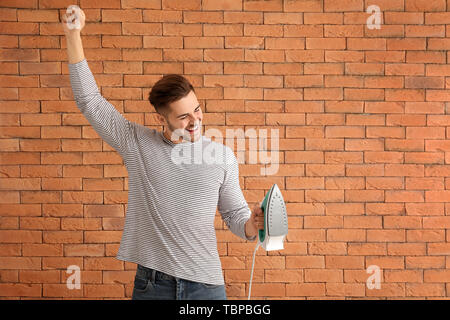 Glückliche junge Mann mit Bügeleisen auf Stein Hintergrund Stockfoto