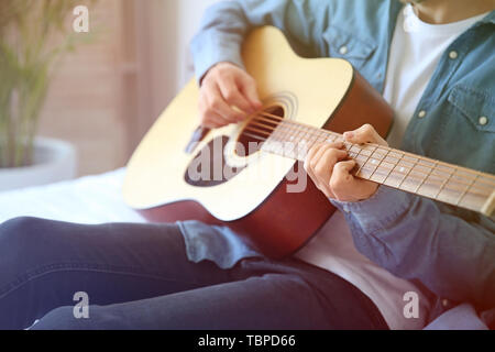 Hübscher junger Mann spielt Gitarre zu Hause Stockfoto