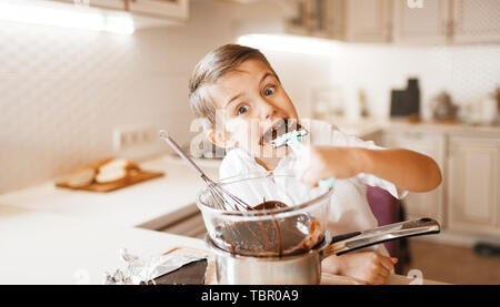 Junge Geschmack geschmolzene Schokolade in eine Schüssel geben. Stockfoto