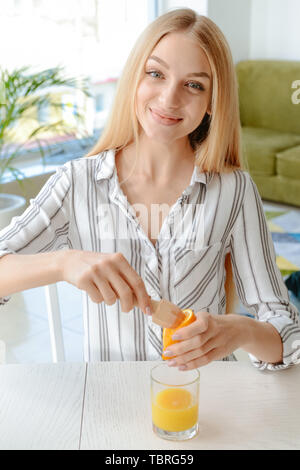 Schöne junge Frau quetschen Saft von Orange zu Hause Stockfoto