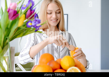 Schöne junge Frau quetschen Saft von Orange zu Hause Stockfoto