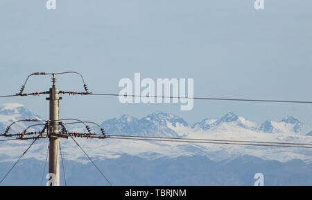 Am südlichen Fuß des Tianshan-gebirges in Xinjiang, unter der majestätischen und heiligen Tianshan Snow Peak, die Windparks und Hochspannungsleitungen der Tianshan Power Line up entlang der Berge für Hunderte von Meilen. Die hoch aufragenden Eisen Türme der Schnee Gipfel ergänzen und das Wort Tianshan Power unter des Tianshan-gebirges sichtbar ist. Windparks und Hochspannungsleitungen Transport Saubere Energie für die kontinuierliche Produktion in Xinjiang. Stockfoto