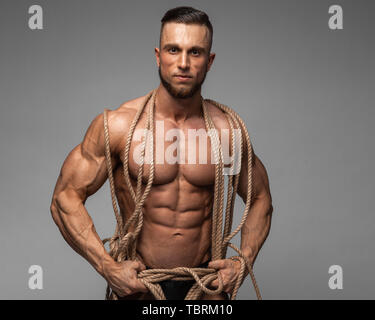 Starke muskulöse Männer gefangen in Seile, die versuchen, zu verlieren. Bodybuilder eingeschlossen in die Seile. Stockfoto