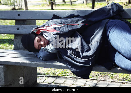 Armen Obdachlosen liegende Frau auf der Bank draußen Stockfoto