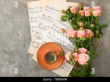 Tasse Kaffee mit Noten und wunderschönen Rosen auf grunge Hintergrund Stockfoto