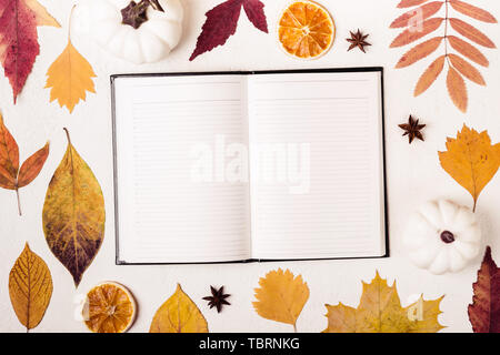 Notepad auf weißen Tisch mit Blätter im Herbst. Stockfoto