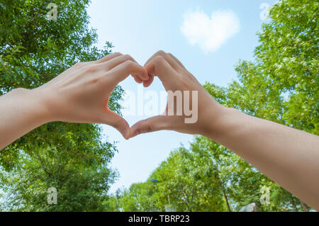 Die zwei Paare vergleichen herzförmigen Gesten, die Herzförmigen Wolken im Himmel. Stockfoto