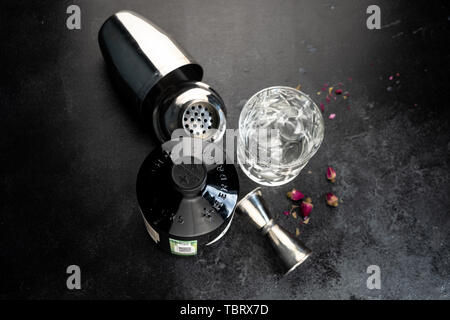 70 cl Flasche Hendricks destillierter Gin mit Glas und Eis auf dunklen rustikalen Hintergrund. Lag neben den Shaker und malenikie rosa Rosen. Stockfoto