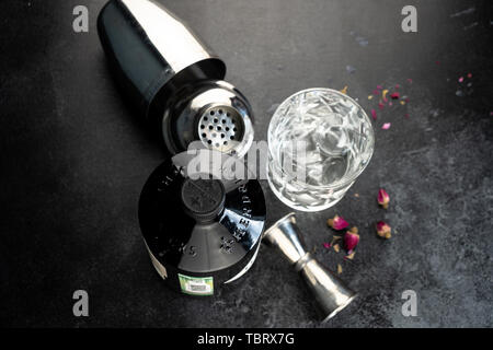 70 cl Flasche Hendricks destillierter Gin mit Glas und Eis auf dunklen rustikalen Hintergrund. Lag neben den Shaker und malenikie rosa Rosen. Stockfoto