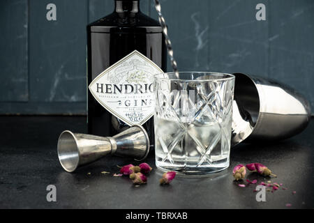 70 cl Flasche Hendricks destillierter Gin mit Glas und Eis auf dunklen rustikalen Hintergrund. Lag neben den Shaker und malenikie rosa Rosen. Stockfoto