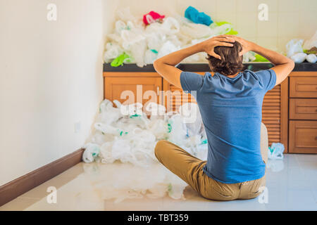 Der Mann verwendet zu viele Plastiktüten, dass Sie die gesamte Küche gefüllt. Null Abfall Konzept. Das Konzept der Tag der Umwelt Stockfoto