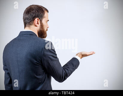 Geschäftsmann in Anzug stehen und zeigt die ausgestreckte Hand mit Öffnen Sie Palm. Stockfoto