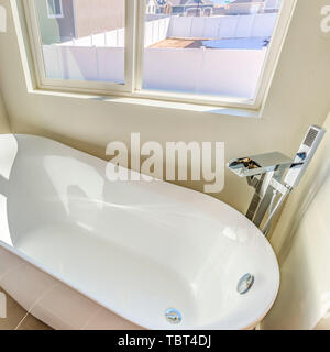 Quadratischen rahmen Bad Interieur mit einem Glaenzenden Badewanne gegen weiße Wand und graue Boden Stockfoto