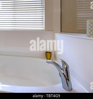 Quadratischen Rahmen strahlend weiße Wanne in einem Badezimmer mit einem großen Spiegel an der Wand Stockfoto