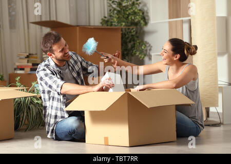 Glückliches Paar Scherzen mit einem Staubtuch reinigen unboxing Sachen Umzug Stockfoto