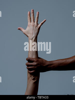 Schwarze Afrikanische amerikanische Hand, die weiße Haut arm. Konzeptionelle Bild der humanitären Kampagne in der Betreuung von Flüchtlingen und Rassismus fragen zu stoppen. Welt Einheit Stockfoto