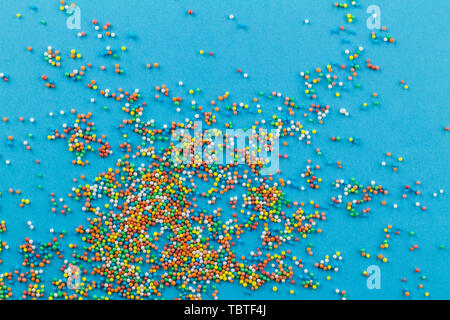 Streusel auf blauem Hintergrund - Kleine runde Kuchen streusel Topping für viele Farben auf hellen Blau Stockfoto